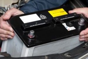 Auto mechanic replacing car battery
