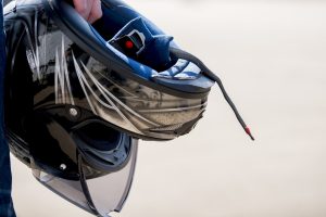 A closeup shot of a male holding his motorcycle helmet with a blurred background