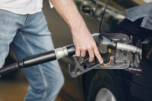 Handsome man pours gasoline into tank of car